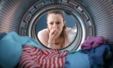 ragazza si tappa il naso con il cestello della lavatrice aperto