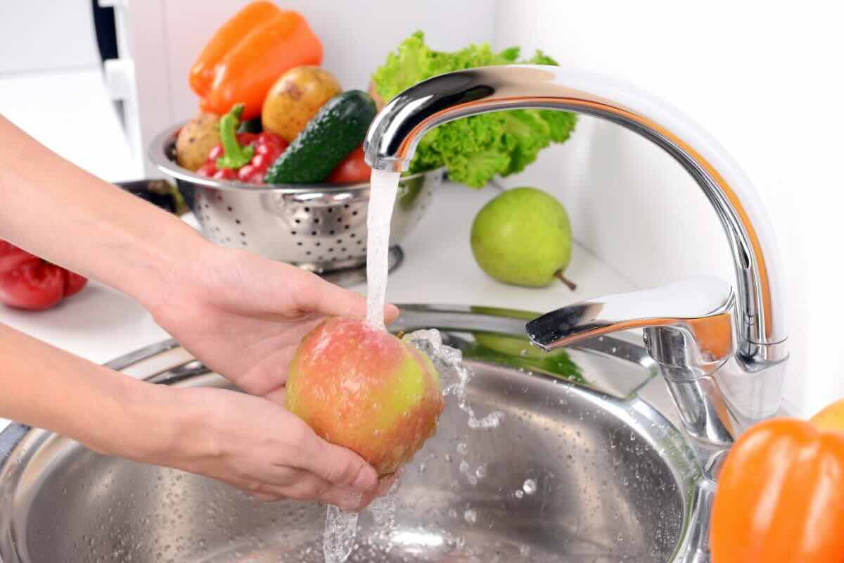 Lavare mela sotto acqua corrente del lavandino