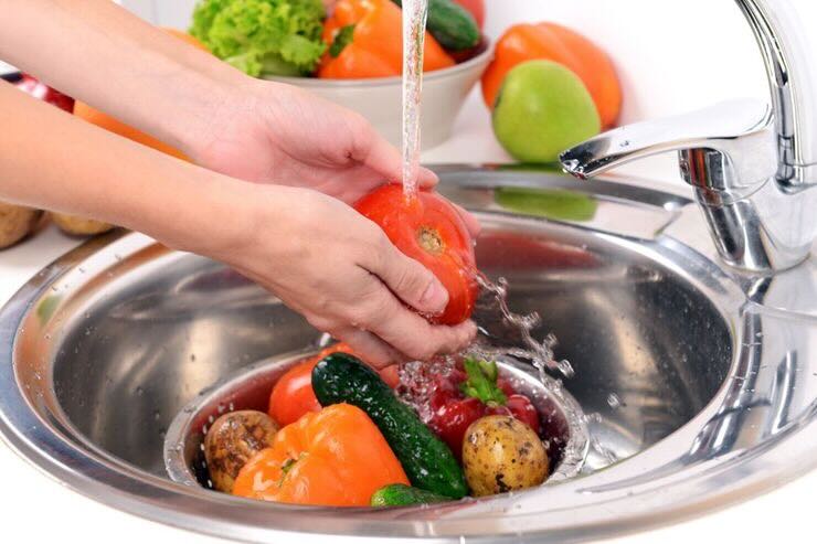 Lavare verdura sotto acqua corrente del lavandino